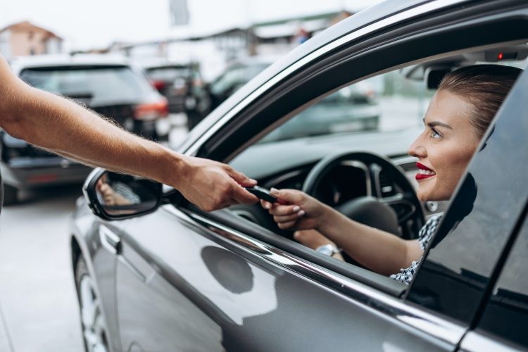 a girl driving a car is given keys