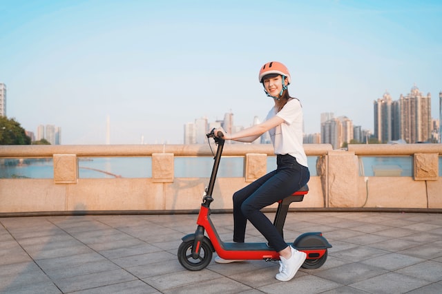 a girl in a white helmet on a red electric scooter
