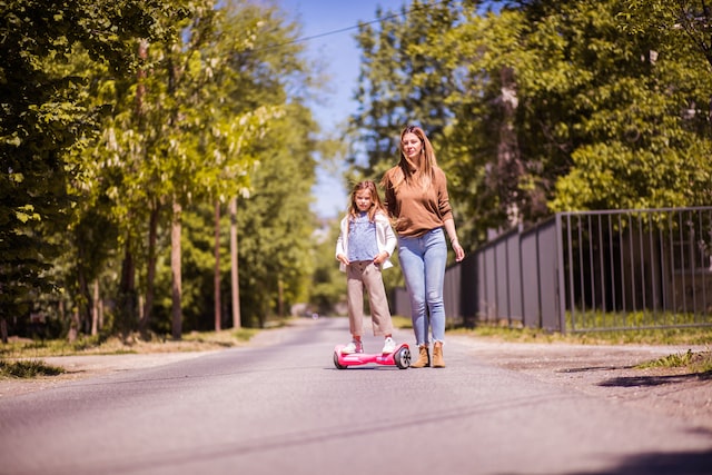 a girl rides a pink hoverboard with her mom