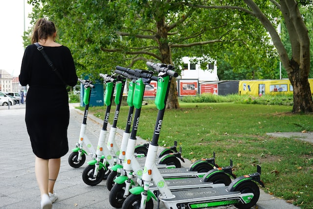 a girl walks past parked electric scooters